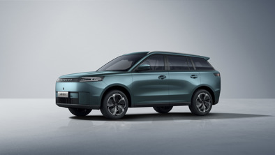 En blågrøn elektrisk JAECOO SUV er parkeret i et minimalistisk studie med en lysegrå baggrund.