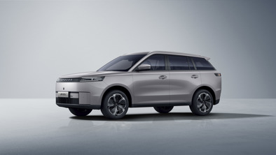 En sølvfarvet JAECOO SUV er parkeret i et minimalistisk indendørs rum med en lysegrå baggrund.