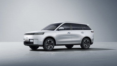 En hvid JAECOO SUV er parkeret på en glat overflade i et minimalistisk indendørs rum med en neutral baggrund.