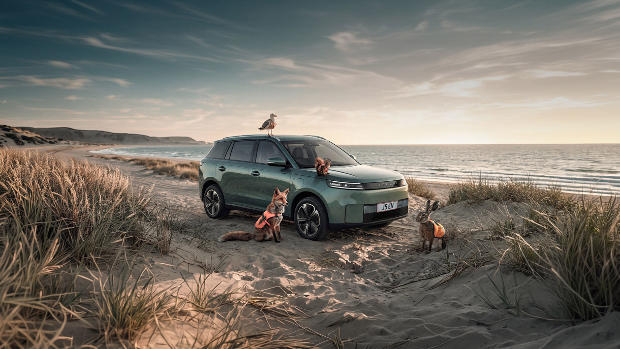 En grøn JAECOO SUV er parkeret på en sandstrand, omgivet af en ræv, hare, egern og måge i orange sikkerhedsvest, med havet synligt i baggrunden.