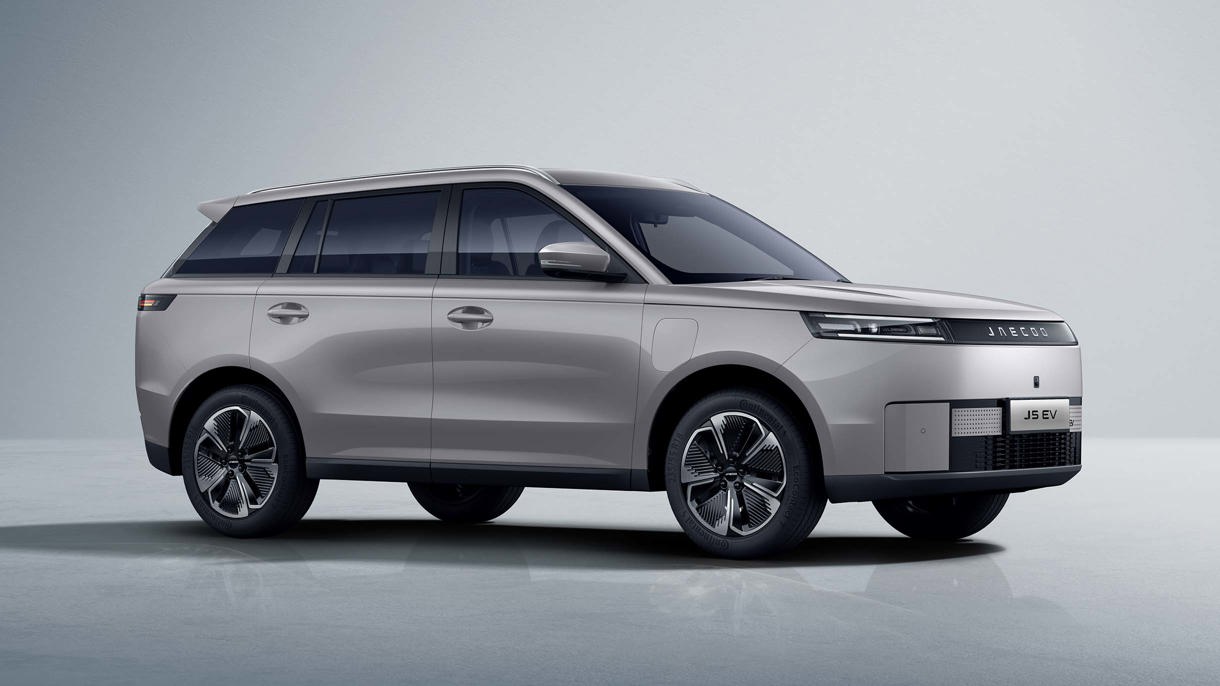 En sølvfarvet JAECOO SUV er parkeret på en glat overflade i et minimalistisk indendørs rum med en neutral baggrund.
