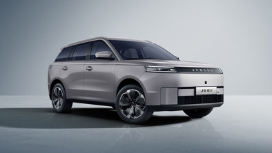 En sølvfarvet elektrisk SUV, JAECOO J5 EV, er parkeret i et minimalistisk studie med en ensfarvet baggrund.